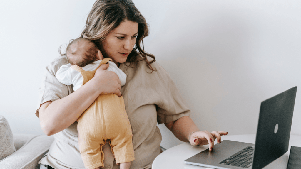 Mom doing work and holding a Baby